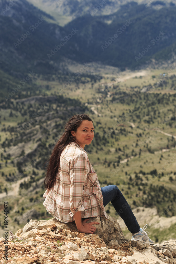 Woman traveller sitting on edge and enjoying mountain view Woman traveller sitting on edge and enjoying mountain view