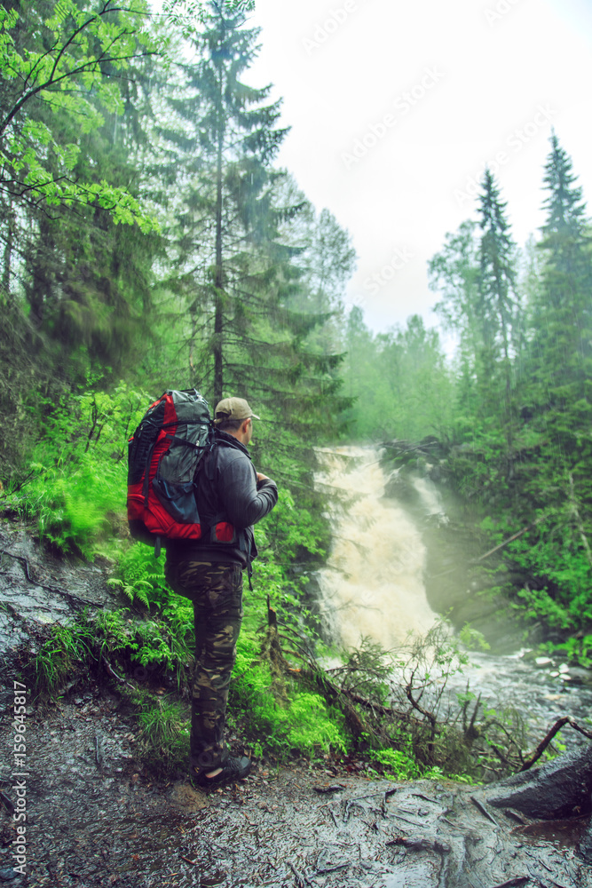 Hiker with a backpack near waterfall. Hiker with a backpack near waterfall.