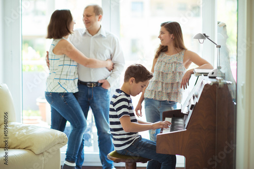 Happy young family listening how cildren plays piano music photo