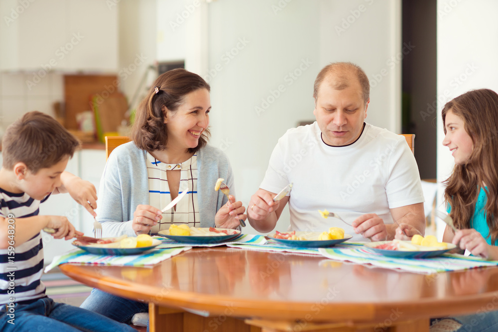 Happy family enjoying dinner at home. Mother, father, daughter, son Happy family enjoying dinner at home. Mother, father, daughter, son