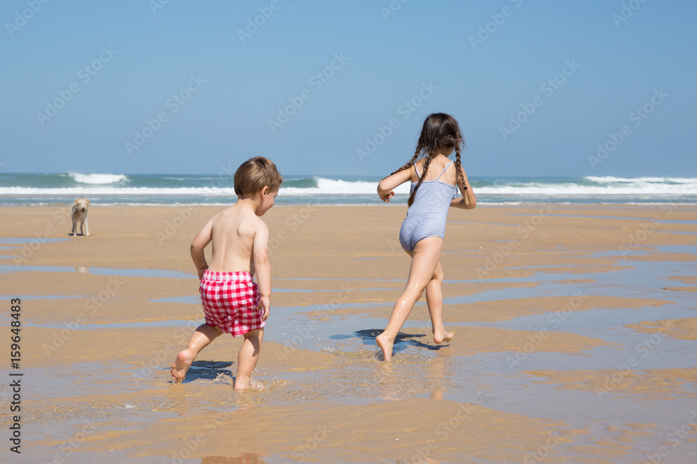 two children run and play in sand beach for summer vacation