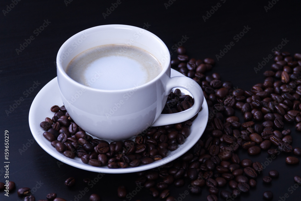 Hot coffee in the white cup and roasted on dark background Hot coffee in the white cup and roasted on dark background