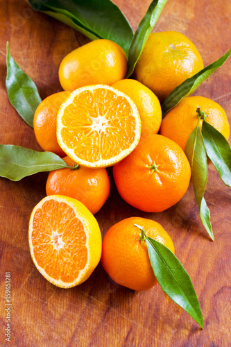 Fresh ripe mandarin oranges with green leaves on wooden table. Ready for making orange juice