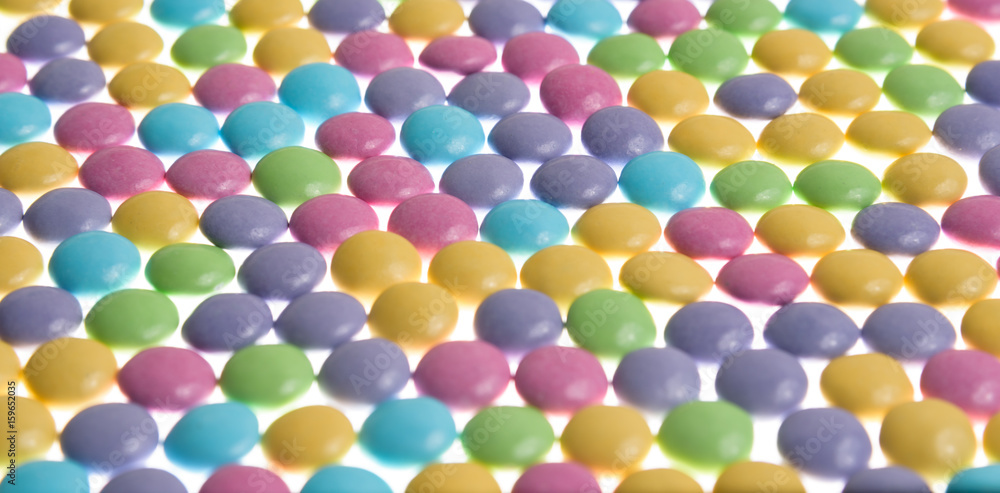 Round pastel candies in a pattern on a white background

