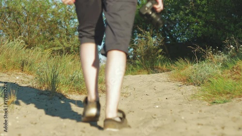 Photographer walks along dunes, in hands of camera photo