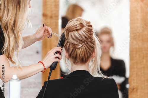 business woman lady boss in beauty salon making hairdress and looking to the mirror