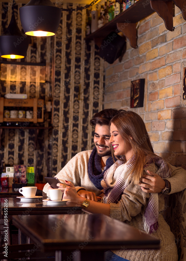 Beautiful young couple looking at tablet in cafe. Beautiful young couple looking at tablet in cafe.
