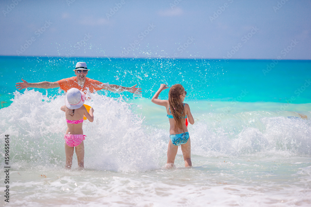Little girls and happy dad having fun on the seashore swimming and running Little girls and happy dad having fun on the seashore swimming and running