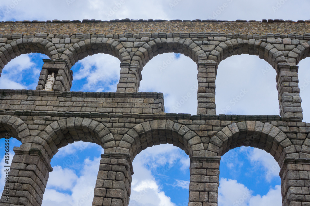 Aqueduct in Spain with the background of blue sky with a lot of clouds in summer, cultural and historical monument