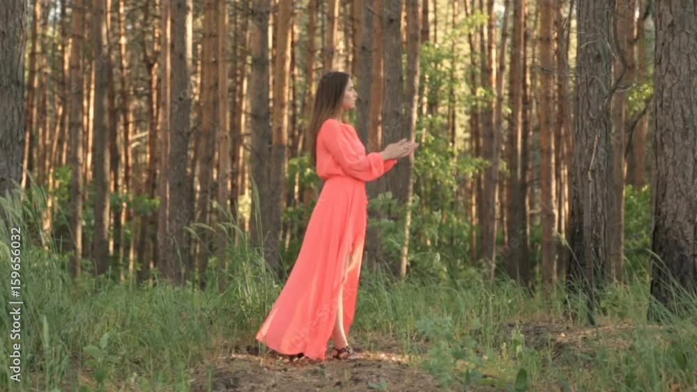 Girl in evening dress in red color in the forest Girl in evening dress in red color in the forest