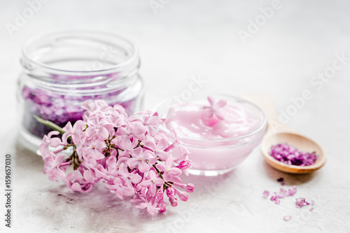 take bath with lilac cosmetic set and blossom on stone table background