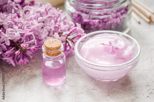 take bath with lilac cosmetic set and blossom on stone table background