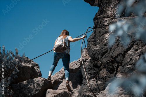 Junge Frau benutzt während einer Wanderung einen Klettersteig 