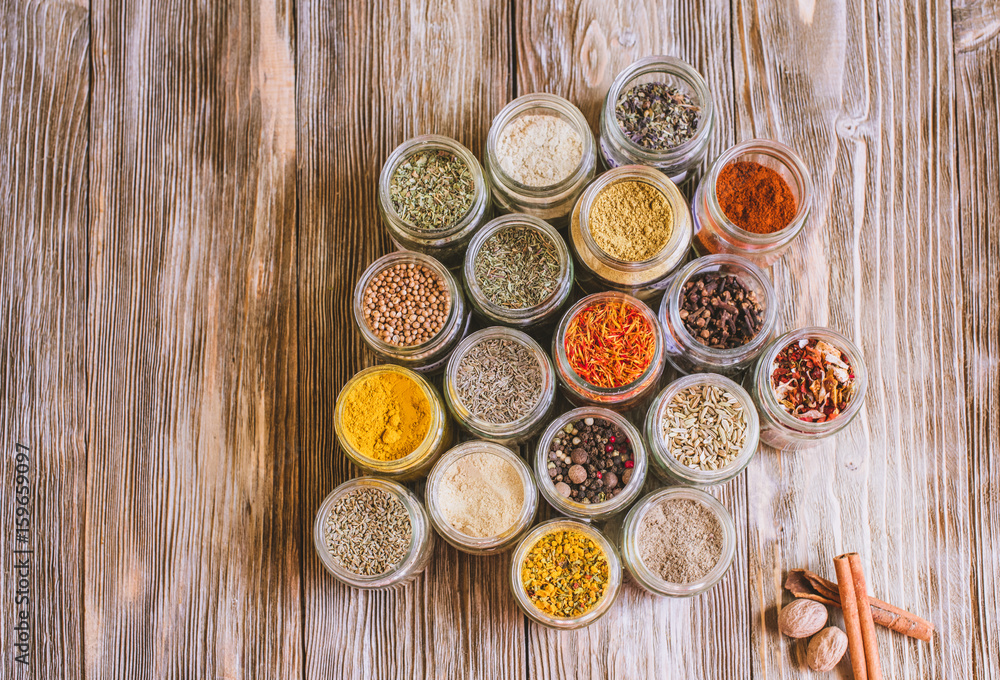 Various colorful kinds of spices on rustic wooden table, top view