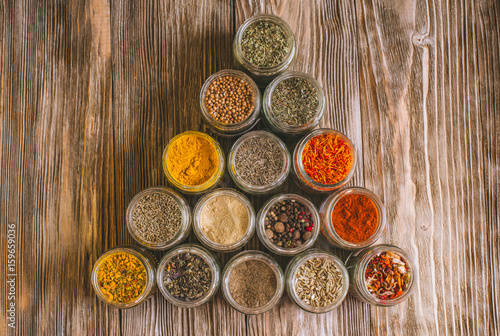 Various colorful kinds of spices on rustic wooden table, top view