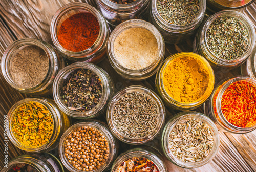 Various colorful kinds of spices on rustic wooden table, top view