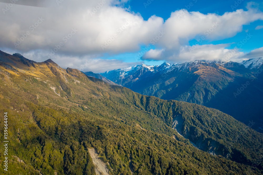 Fototapeta premium Beautiful landscape of the New Zealand - hills covered by green grass with mighty mountains covered by snow behind, South Island in New Zealand