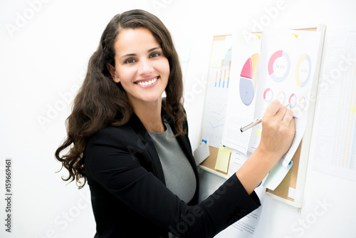 Smiling businesswoman presenting data on the board