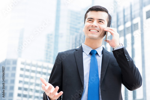 Businessman calling on smartphone with hand gesture in blur office building background