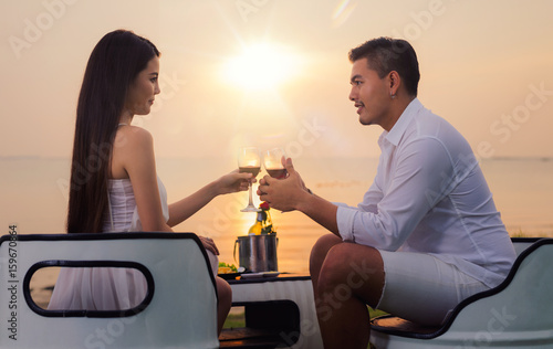 Asian couple in romantic dinner with sea beach and sunset in Thialand island photo