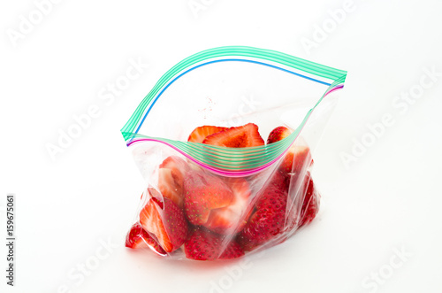 Studio shot fresh chopped strawberries in clear open plastic bag with lock isolated on white. In-house cut, packed strawberry in transparent zipper bags to-go/take away. Convenience, healthy lifestyle photo