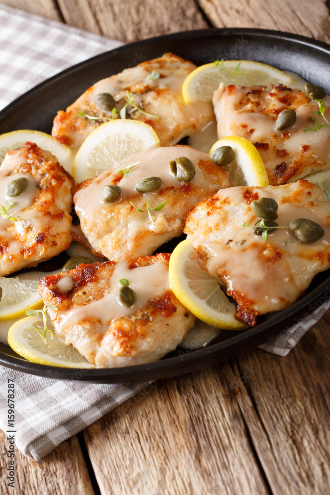 Plate with chicken piccata on wooden board closeup. Vertical Plate with chicken piccata on wooden board closeup. Vertical