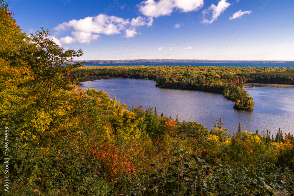 Michigan Autumn Scenic Panorama. Vibrant autumn color in the northern Michigan forest with the vast blue waters of Lake Superior in the background. Spectacle Lake overlook in Brimley, Michigan.