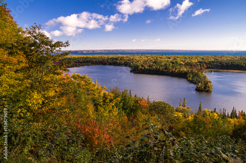 Michigan Autumn Scenic Panorama. Vibrant autumn color in the northern Michigan forest with the vast blue waters of Lake Superior in the background. Spectacle Lake overlook in Brimley  Michigan.