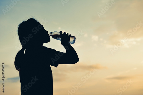 Silhouette women drinking water at sky sunset background ,color style hipster tone