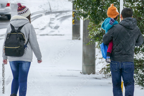 雪道を歩く親子の後ろ姿
