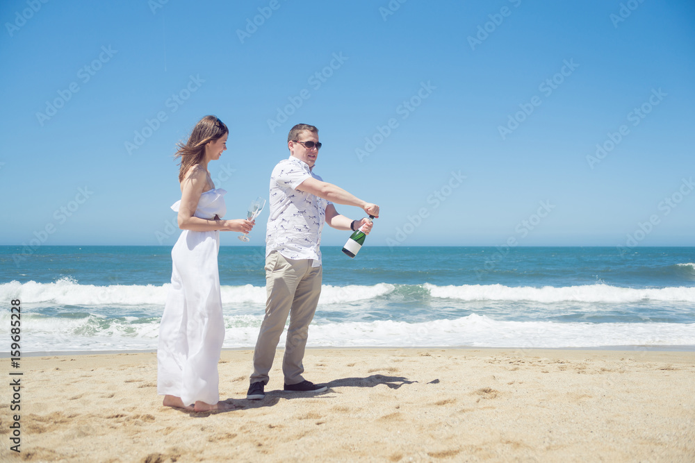 Happy couple on the beach with champagne