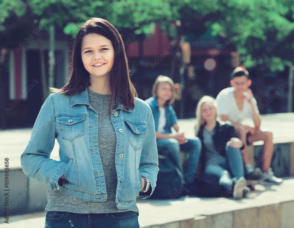 Portrait of  teenager girl standing aside from friends outdoors