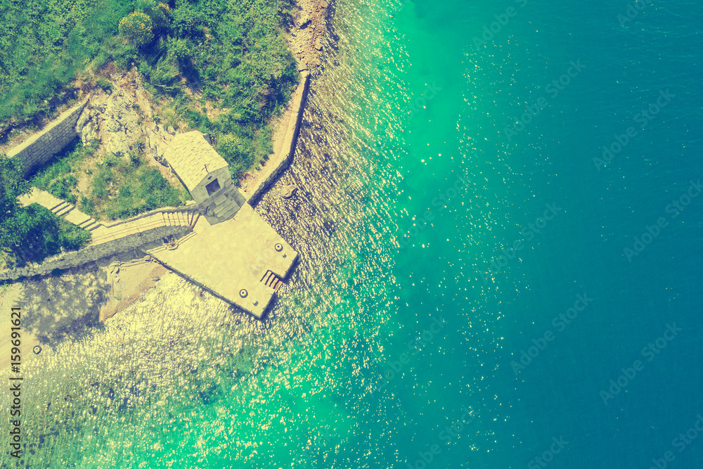 Stone building with a cross on the sea shore, top view. Toned