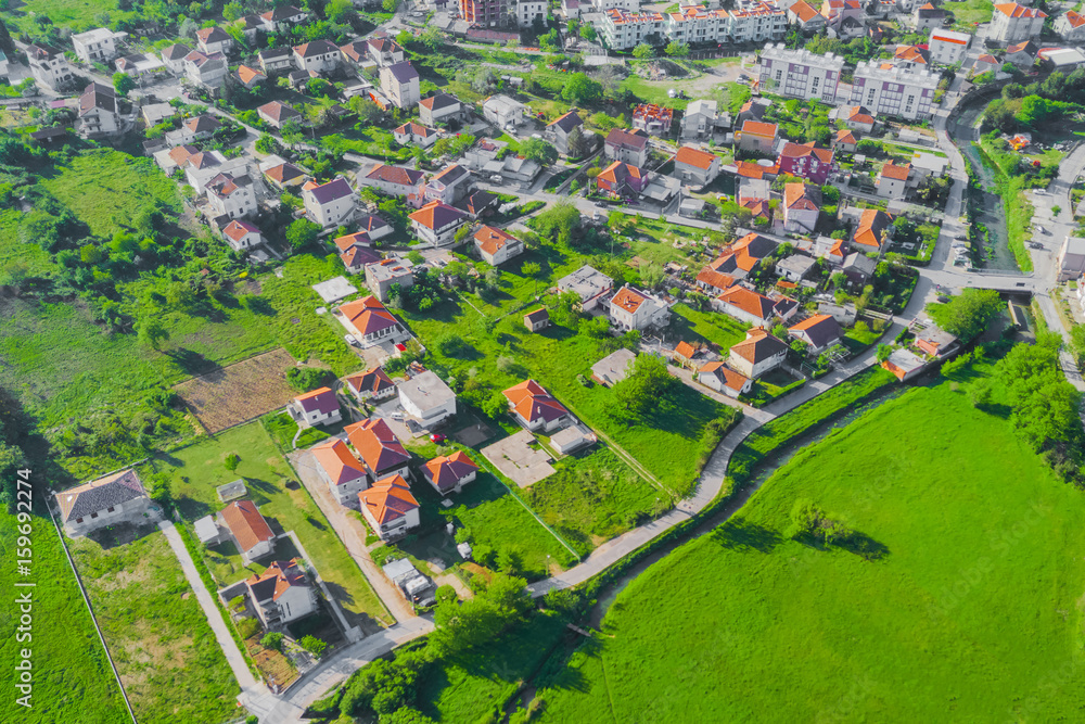 Top view of the village houses with red tiled roof on the green grass