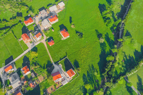 Top view of the village houses with red tiled roof on the green grass