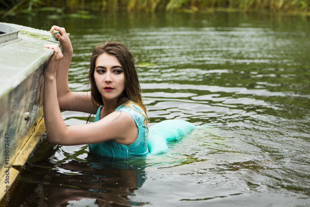 Fototapeta premium The woman swims in the dirty river
