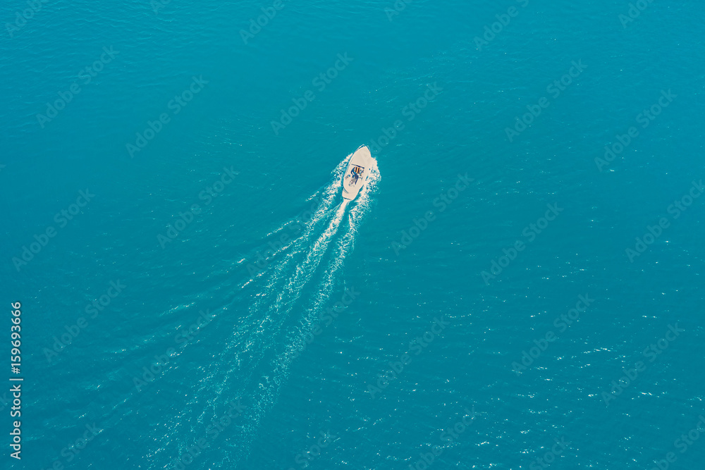 Obraz premium Top view of a white boat sailing in the blue sea