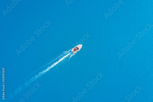 Top view of a white boat sailing in the blue sea © watman