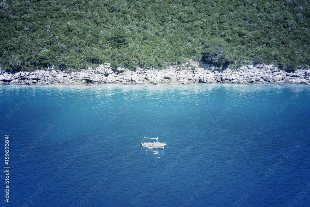 Naklejka premium White boat floating near a rocky shore