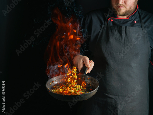 Fotografie Cooking of vegetable mix stew with tossing on a hot frying pan in the tongues of flame