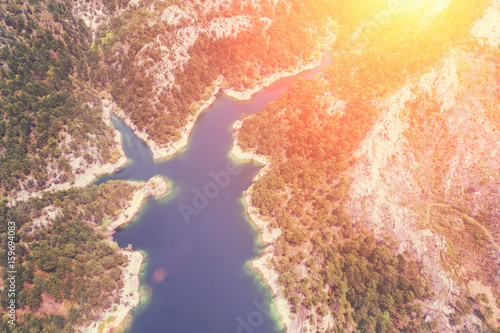 Top view of a lake surrounded by forest in the sunlight