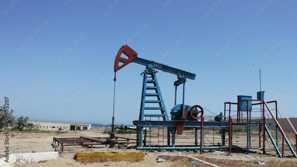Oil pumpjacks in a working oil field in Baku, Azerbaijan.Silhouette of working oil pump on a background of blue sky and clouds.Oil fields Oil pumpjacks in a working oil field in Baku, Azerbaijan.Silhouette of working oil pump on a background of blue sky and clouds.Oil fields