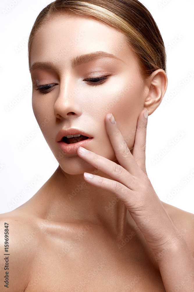 Young girl with perfect shining skin. A beautiful model with a foundation and nude makeup. Clean skin. White isolated background. Beauty of the face.