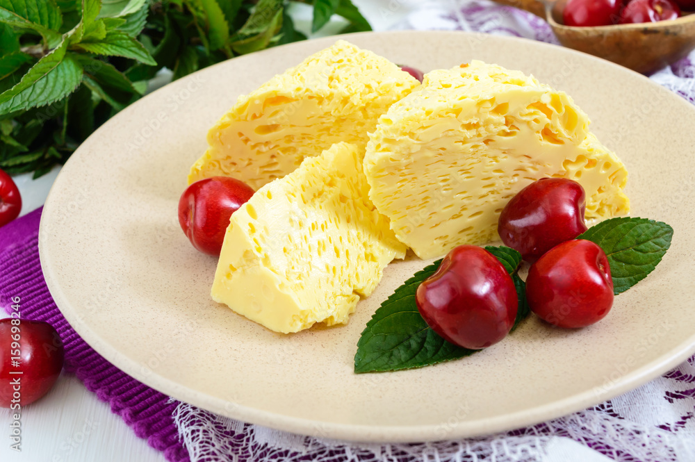 Air milky-vanilla pudding with ripe cherries and mint leaves on a plate ...