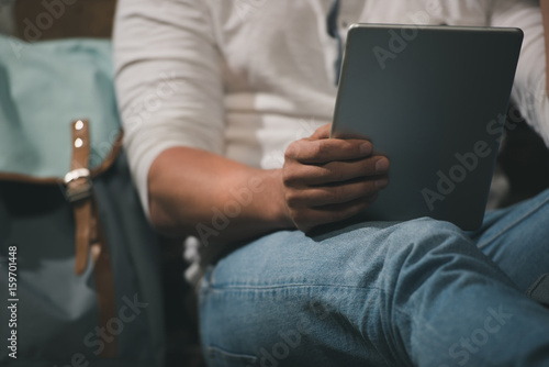 Cropped shot of man sitting and reading on digital tablet. Selective focus on digital device