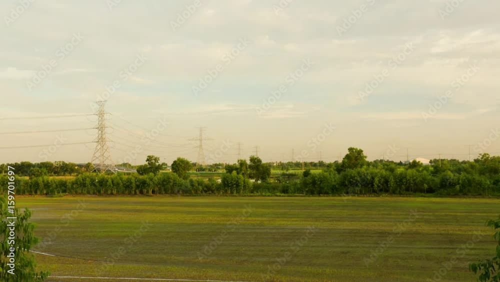 Time lapse moving clouds rice field and car in highway on sunset background.