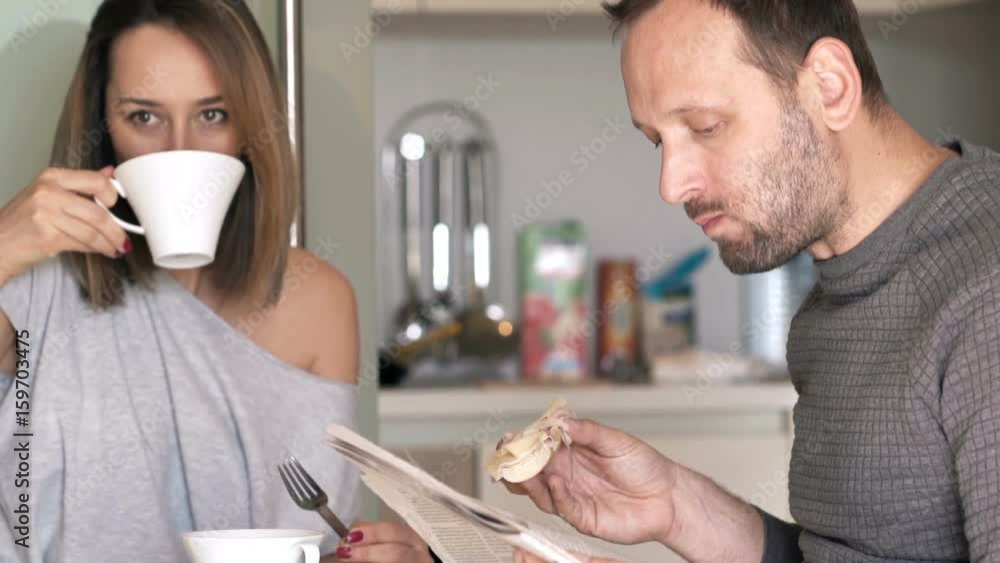 Young couple eating breakfast at home, man reading newspaper
Young couple eating breakfast at home, man reading newspaper