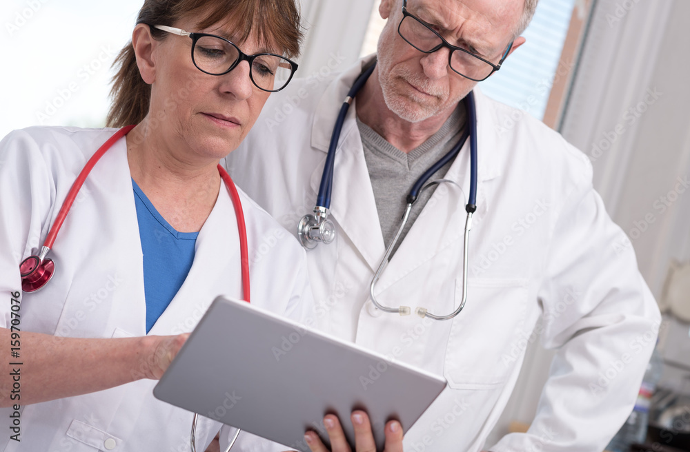 Two doctors discussing about medical report on tablet Two doctors discussing about medical report on tablet