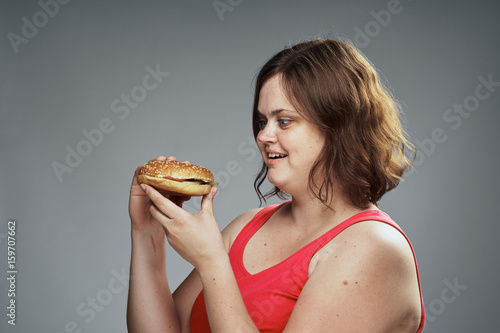 Hungry woman looking at a hamburger, woman with a hamburger on a gray background