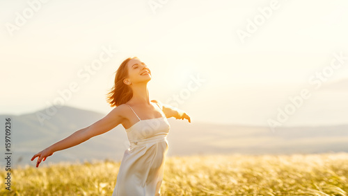 Happy woman standing with her back on sunset in nature iwith open hands